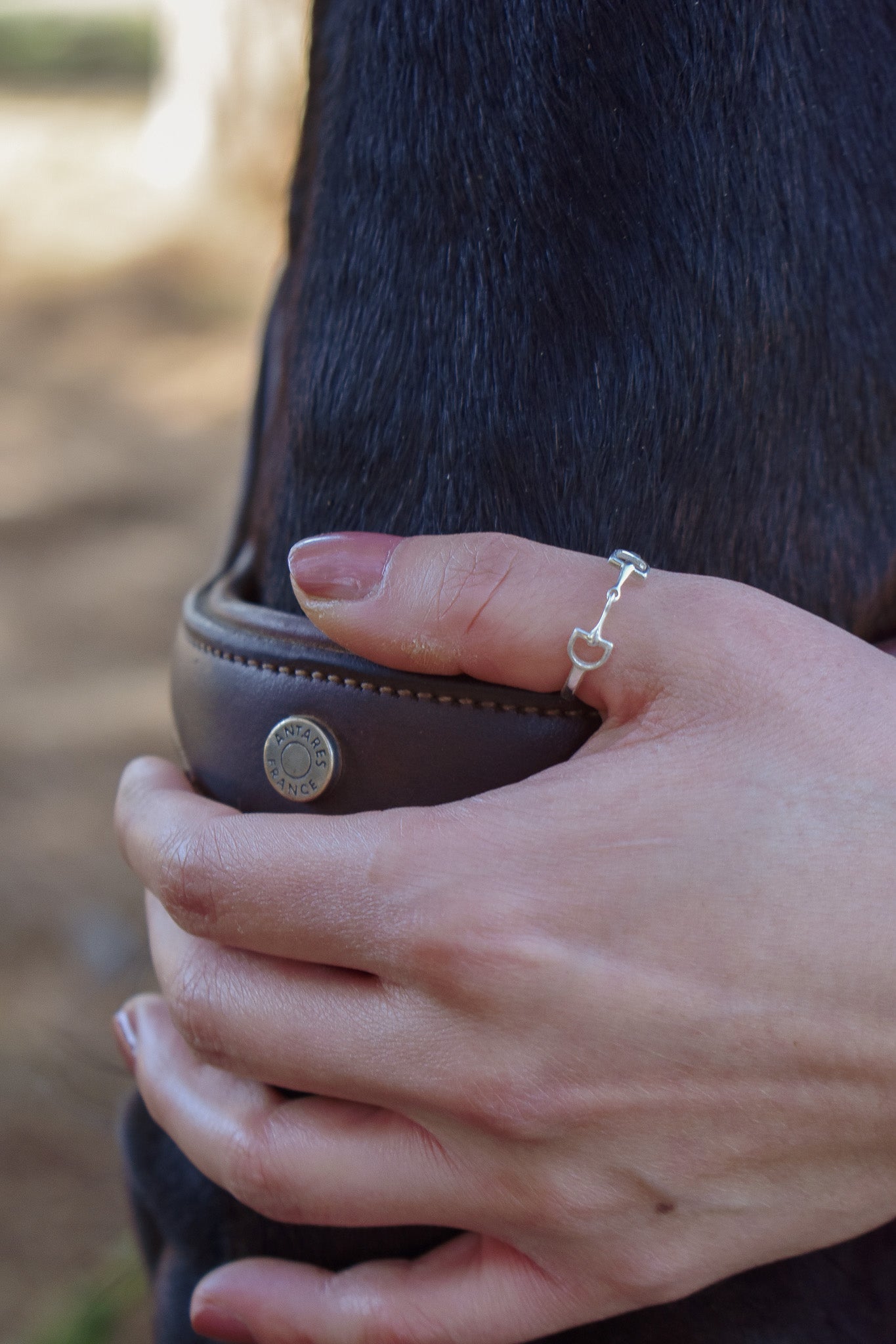 Bit ring on model's hand, holding the bridle on a horses nose