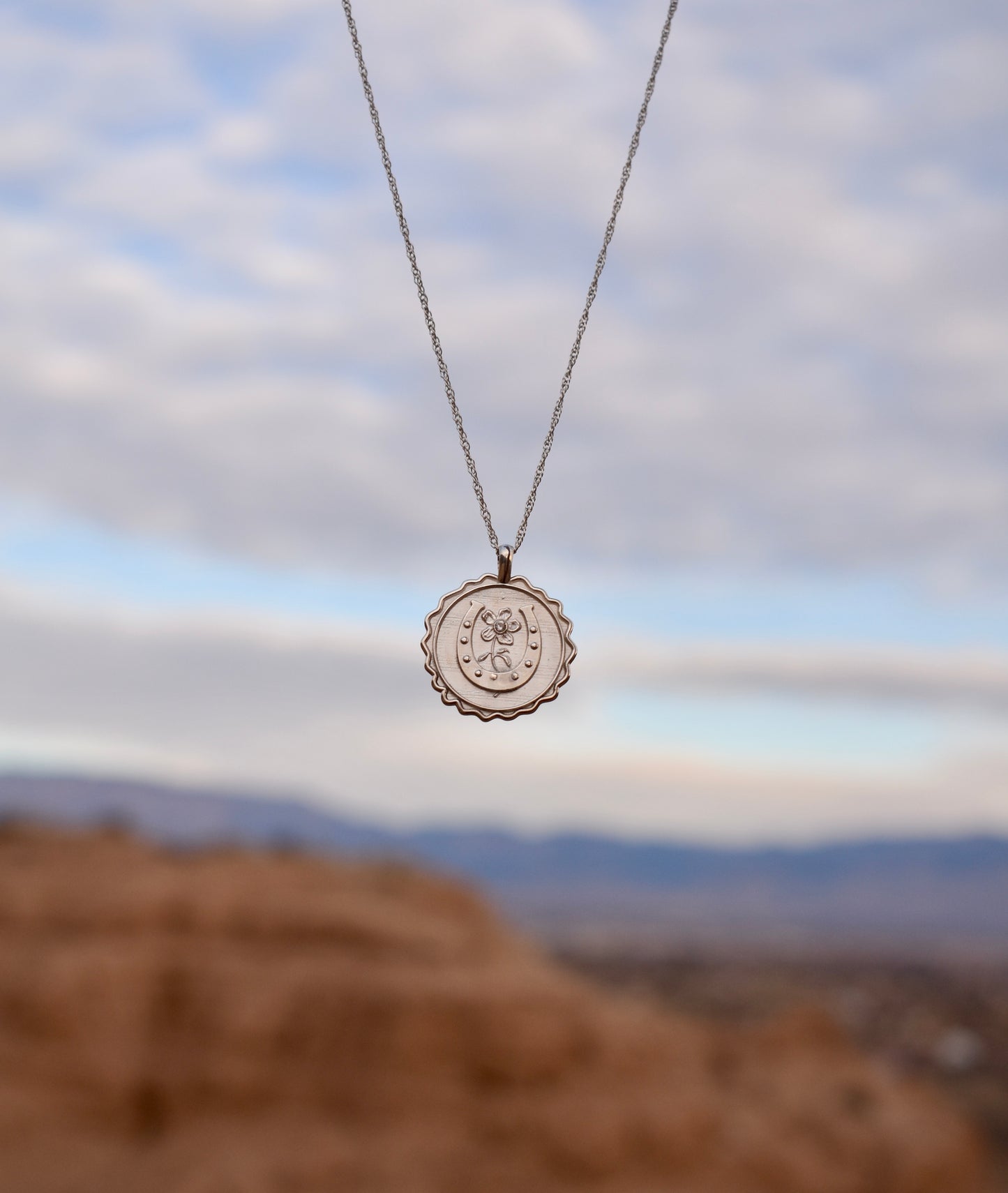 Sterling Silver good luck amulet with the New Mexico mountains in the background