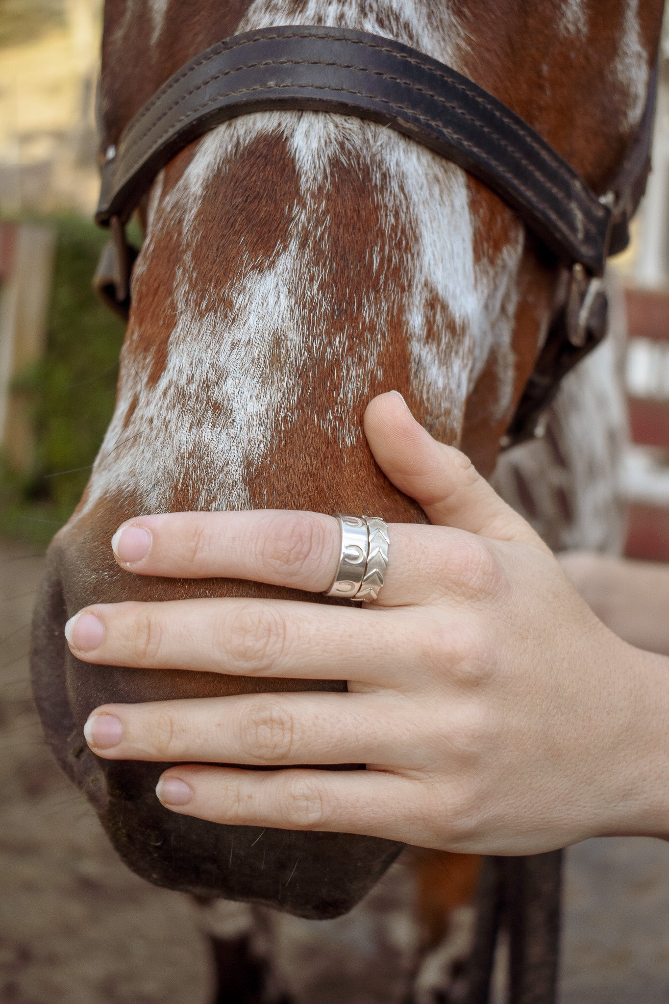 Model holding horses nose with the good luck ring stacked on the reigns ring