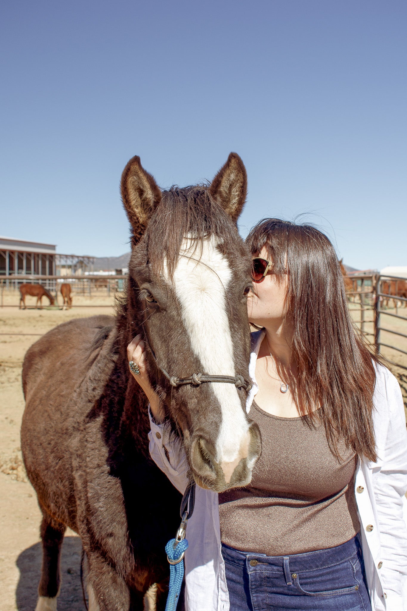 Horse looking directly at camera while model wearing sterling silver horseshoe pendant kisses the cheek