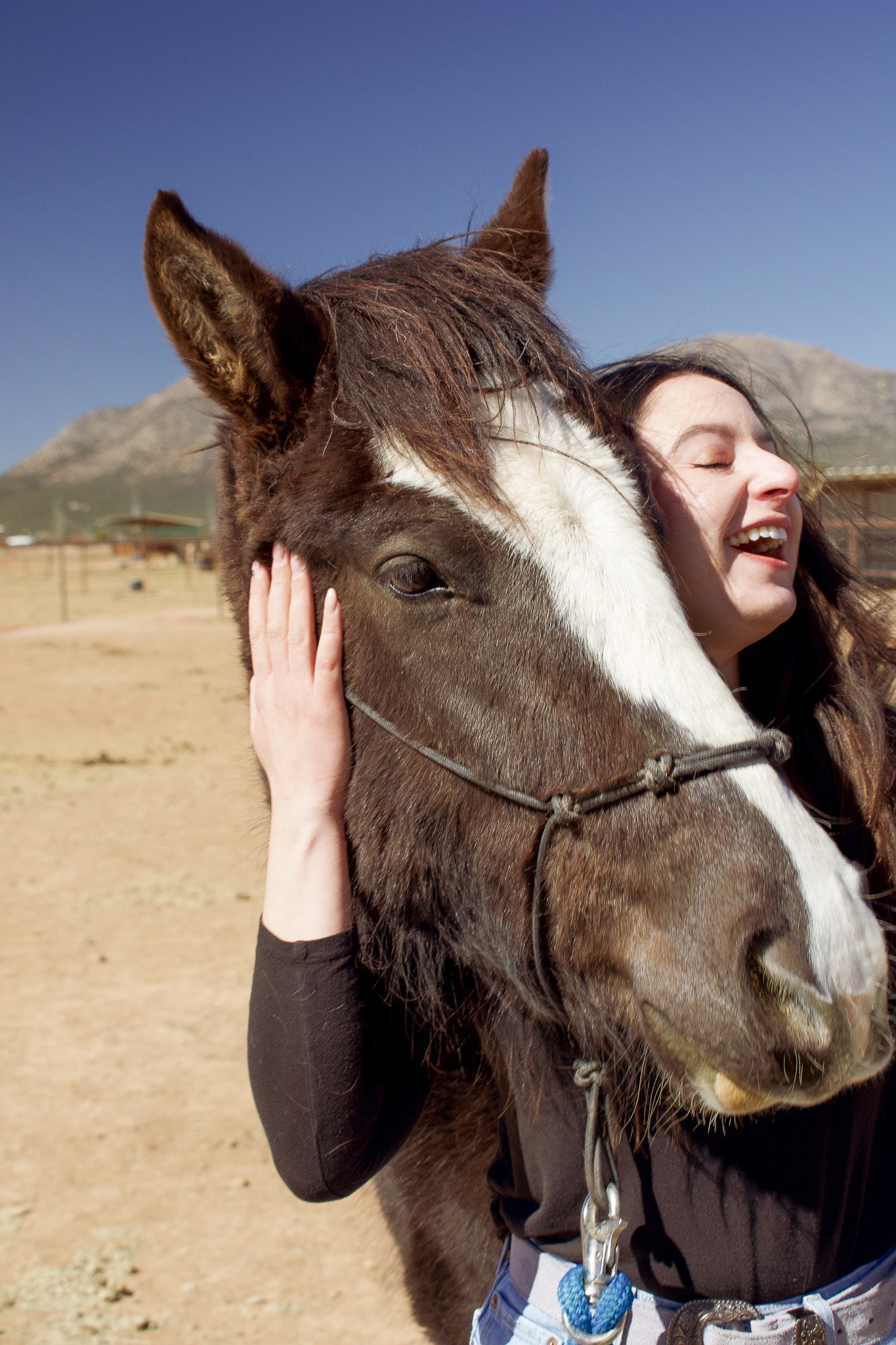 Model laughing and hugging a horse at New Mexico Horse rescue