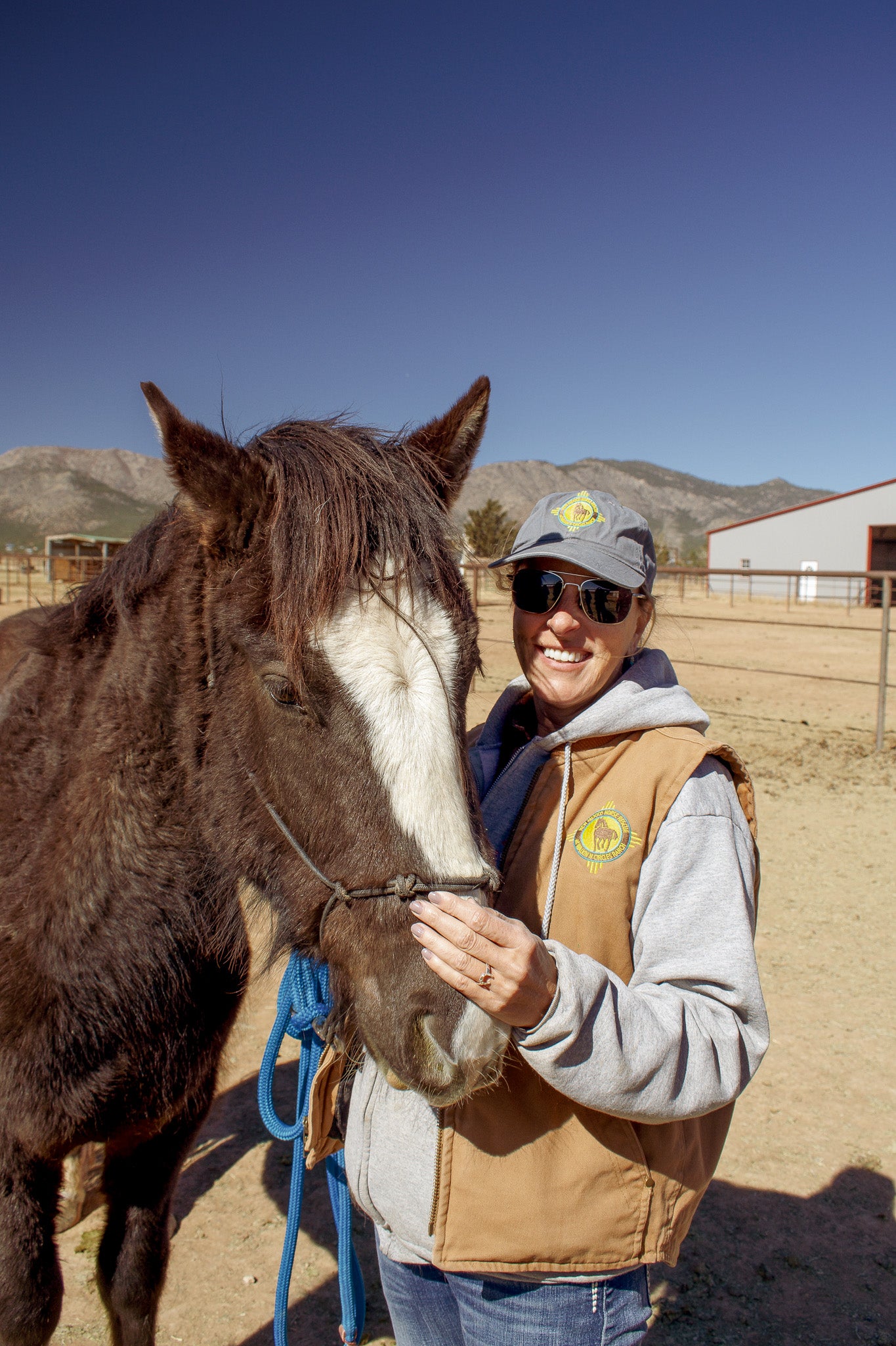 Director of New Mexico Horse Rescue holding horse and smiling