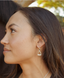 Side profile of a model with the stirrup huggies in sterling silver by Saddle and Stone